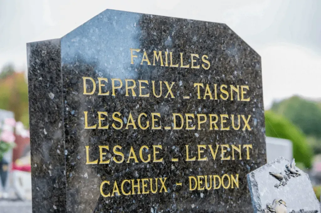 Stèle funéraire en granit noir avec lettrage gravé à la feuille d'or indiquant les noms des familles.