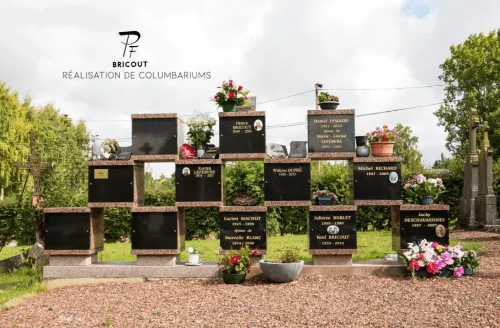 Réalisation d'un columbarium extérieur modulaire en granit par les Pompes Funèbres Bricout, garni de plaques et de fleurs.