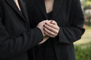 Gestes de soutien et de condoléances entre proches vêtus de noir.